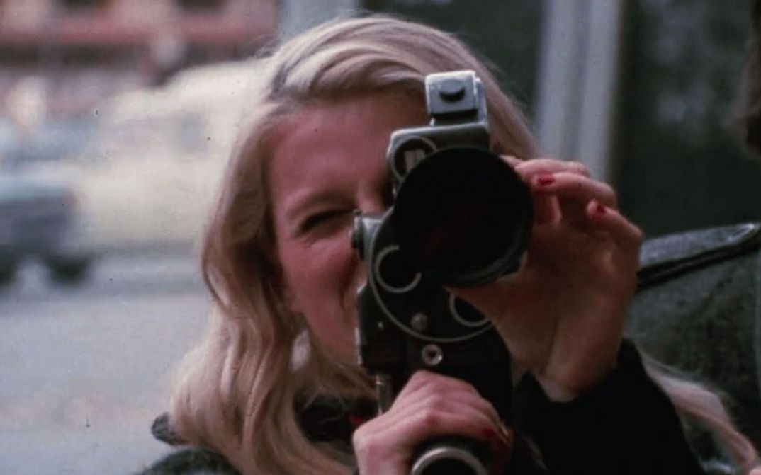 Film still from PLACE DE LA REPUBLIQUE: A woman holds a camera up to the viewer
