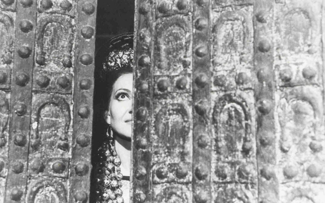 Film still from MEDEA. Maria Callas as Medea looks through a crack in the door.