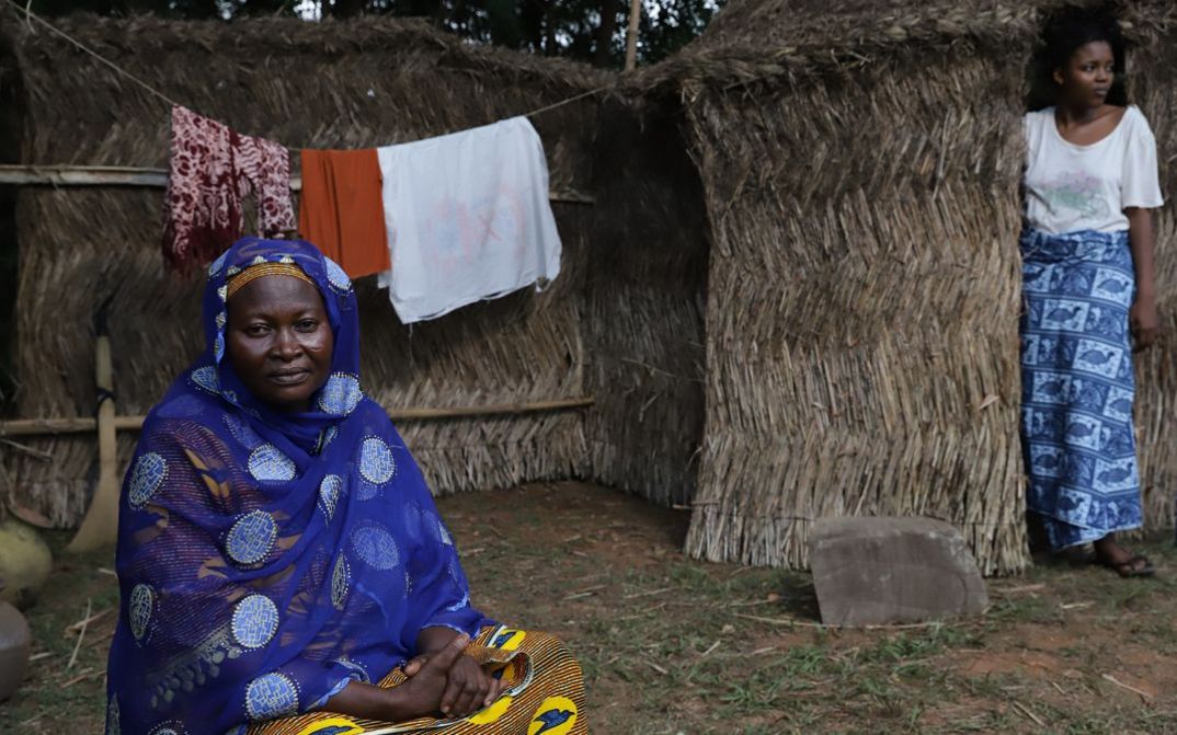 Filmstill aus dem Film „CERTAIN WINDS FROM THE SOUTH“ von Eric Gyamfi. Eine Person blickt sanft in die Kamera, während eine andere aus dem Bild starrt, eine Wäscheleine im Rücken.
