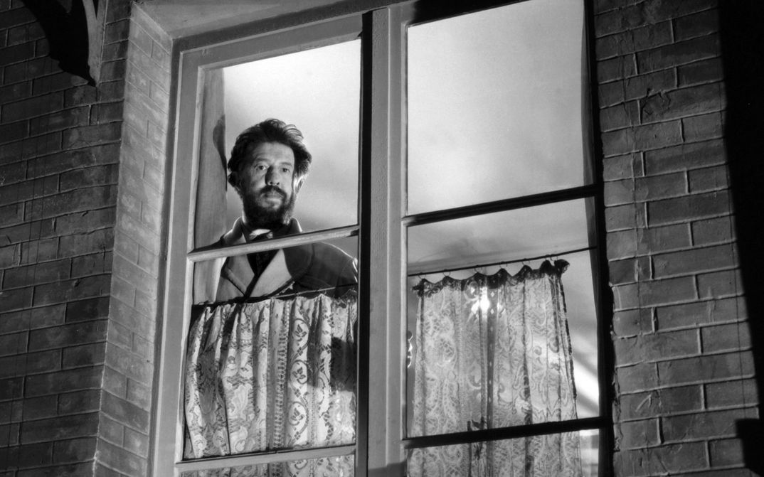 Film still from PANIQUE: A man looks through a window to the outside.