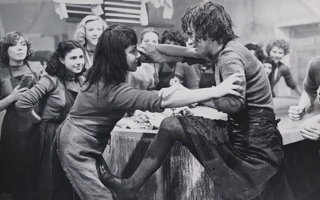 Fillm still from AU ROYAUME DES CIEUX: Two young women fighting with each other, in the background some observers.