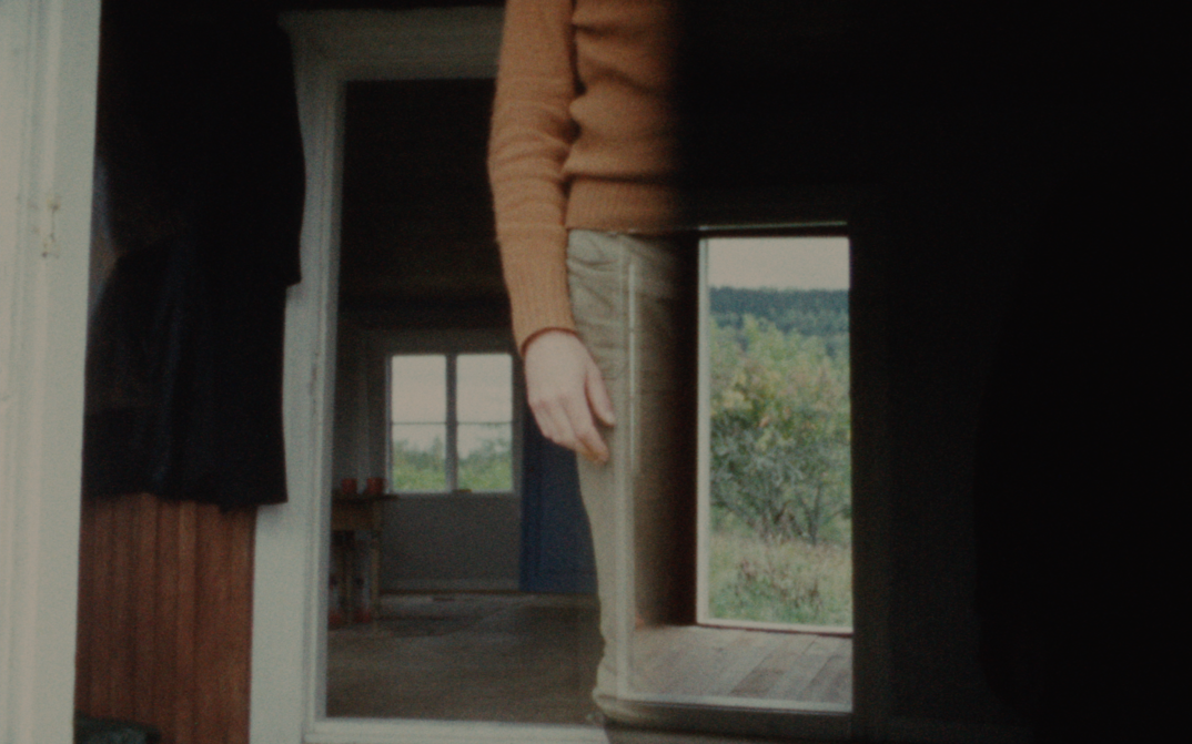 Film still from KASKARA: One sees superimposed images; the interior of a house, the body of a person without the head.