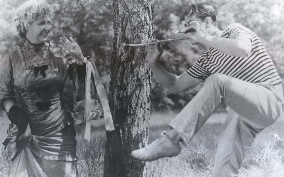 Film still from PARTIE DE CAMPAGNE: A man and a woman in an exuberant mood in a park.