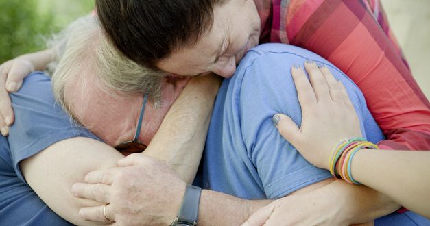 Film still from HOLDING LIAT by Brandon Kramer. The picture shows three crying people hugging each other. 