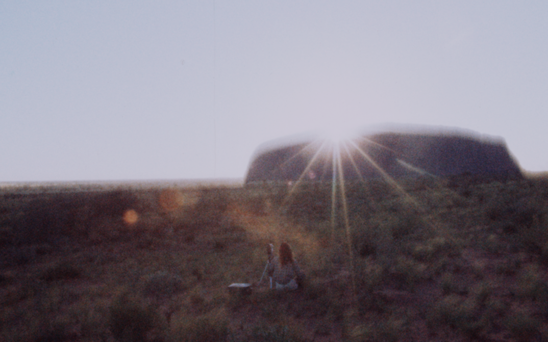 Film still from THE SECOND JOURNEY (TO ULURU): The sun rises behind Mount Uluru and shines directly into the camera.