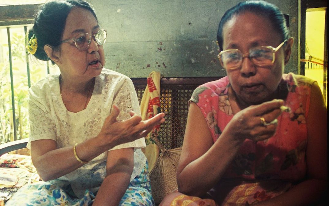 Film still from FRIENDS IN HIGH PLACES: wo women sitting next to each other talking.