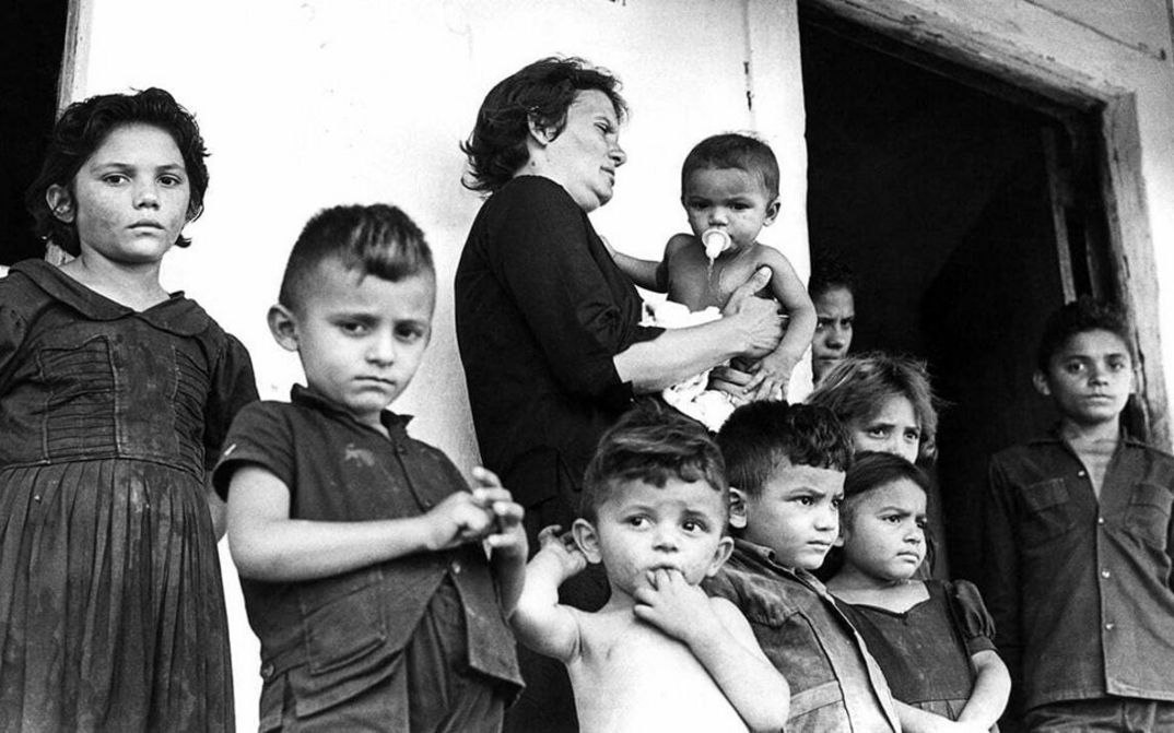 Film still from CABRA MARCADO PARA MORRER: A large family in front of a simple house.