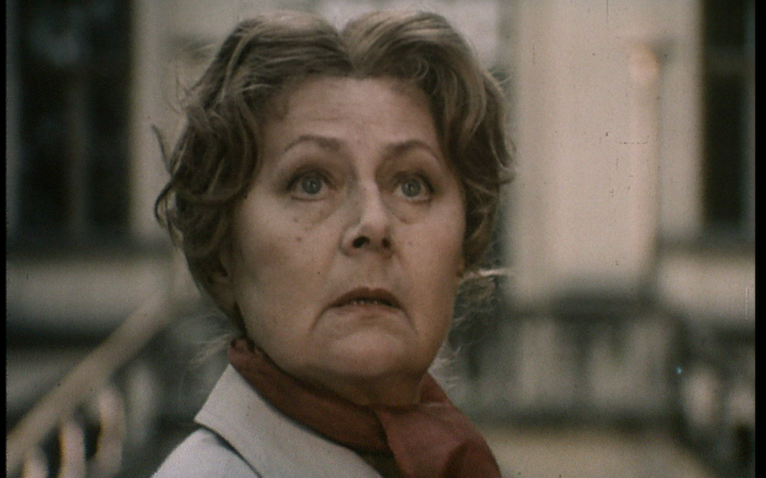 Film still from THE INVITATION: An older woman glances up.