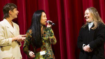 Three women in front of a red curtain. 