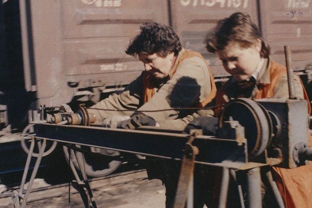 Film still from ORANGE VESTS: Two female workers in orange vests at work on a railroad track.