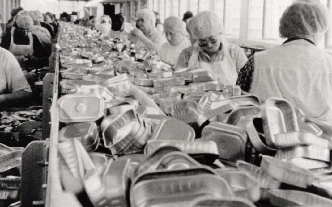 Film still from BELFAST, MAINE. Women work on the assembly line of a factory.