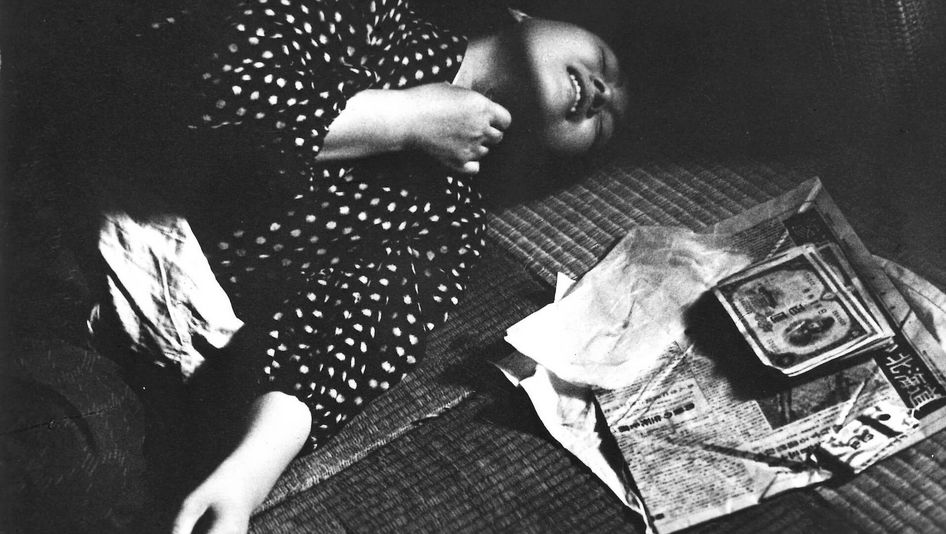 Film still from A FUGITIVE FROM THE PAST: A woman lies on a tatami covered floor with a desperate expression on her face.