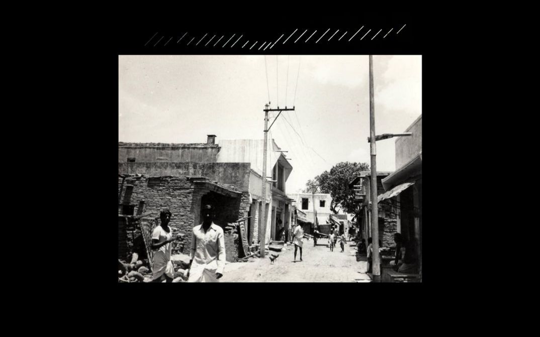 Still from “beneath the placid lake” by Kush Badhwar and Vyjayanthi Rao. On a black background, a black and white film is projected onto a screen.