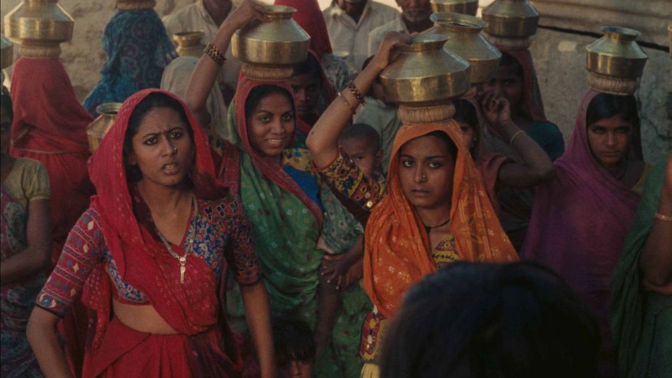 Film still from MANTHAN: Some women in colorful saris wear vessels on their heads.