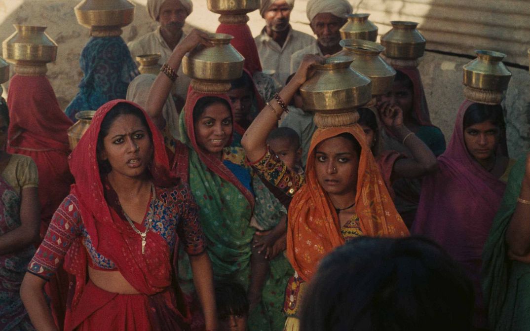 Film still from MANTHAN: Some women in colorful saris wear vessels on their heads.