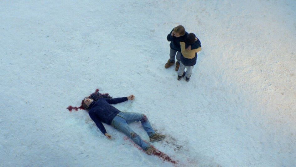 Filmstill aus ANATOMIE EINES FALLS: Aus der Vogelperspektive: Ein Mann liegt im Schnee. Um ihn herum ist Blut. Wenige Meter entfernt steht eine Frau, die telefoniert und ein Junge.