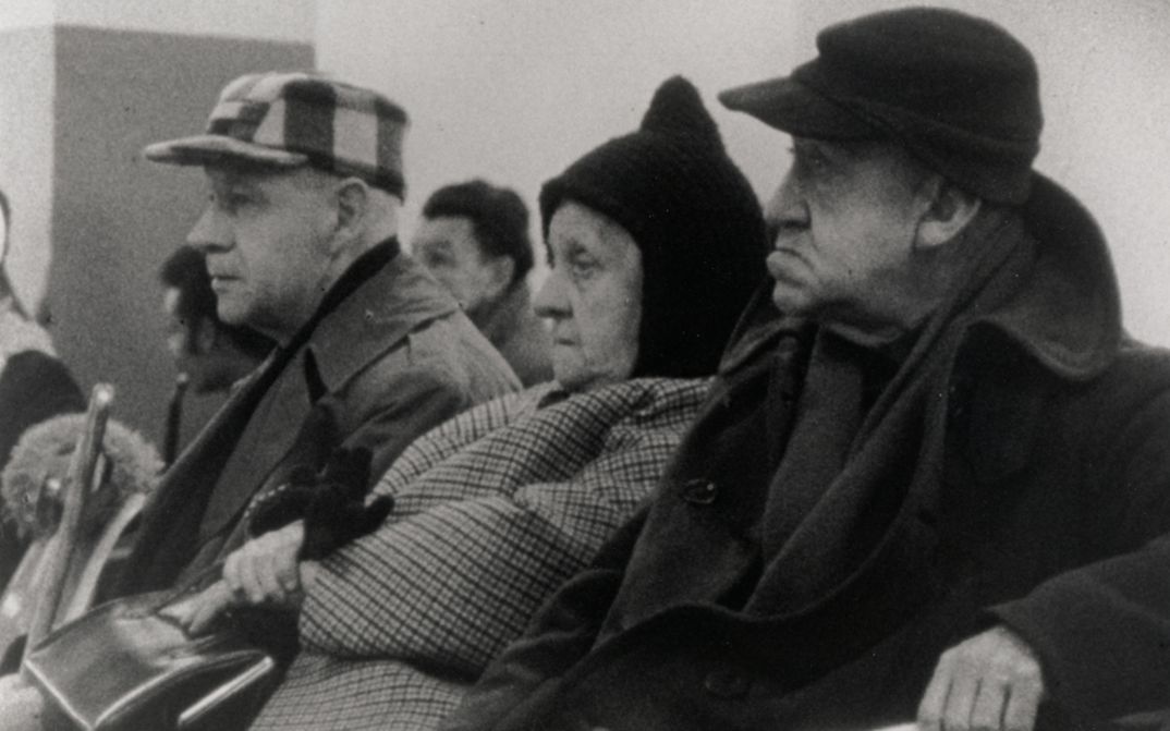 Film still from WELFARE. Three elderly people are sitting in a waiting room.