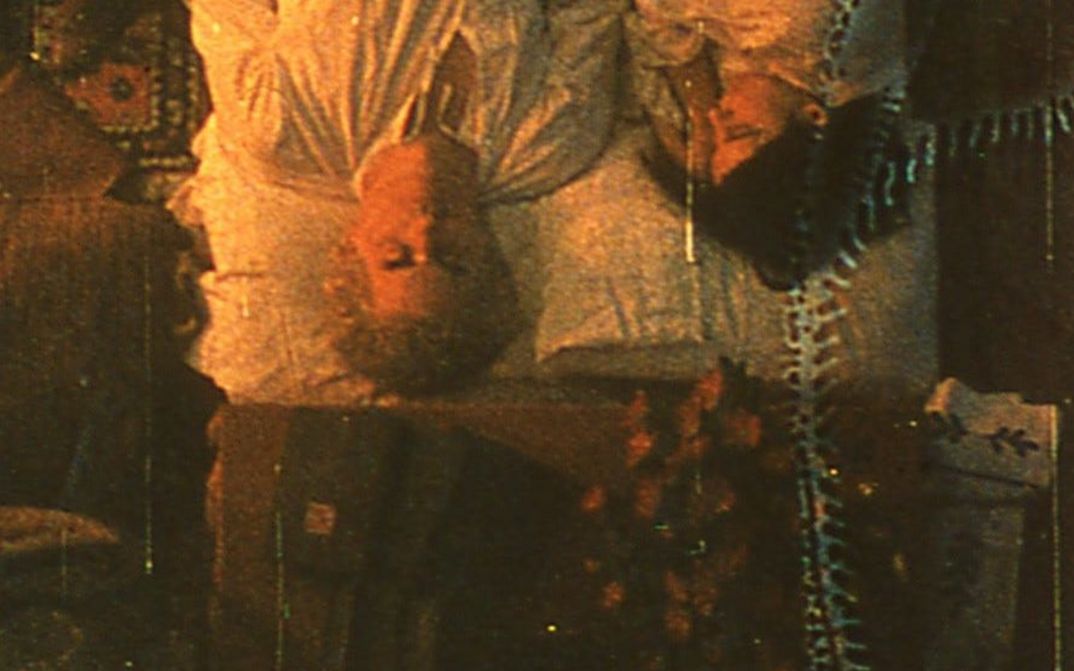 Film still from TO LAVOISIER, WHO DIED IN THE REIGN OF TERROR: Top view of a couple lying in bed. The film material has clearly been altered and shows streaks and stains.
