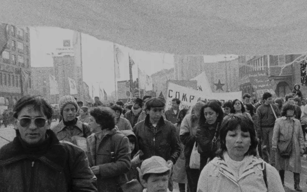 Film still from EXIL: You see people on a demonstration, in the background some banners.