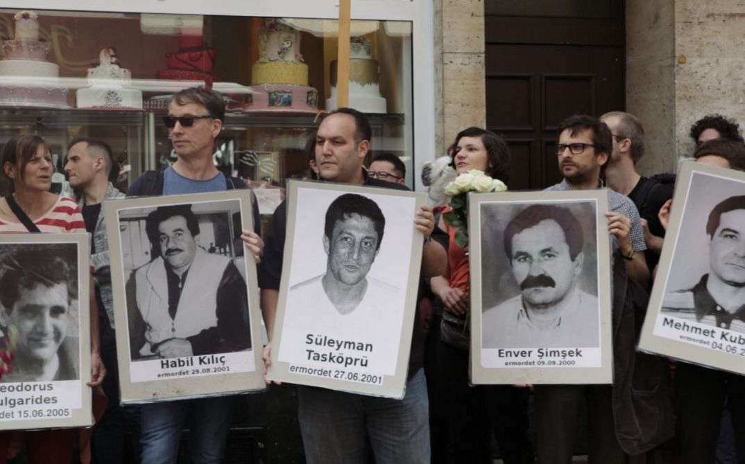 DER ZWEITE ANSCHLAG (Still): Menschen draußen halten Fotos hoch