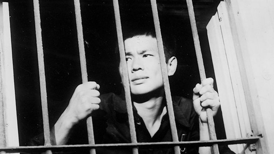 Film still from BAD BOYS: A young man clings to the bars of a barred window.