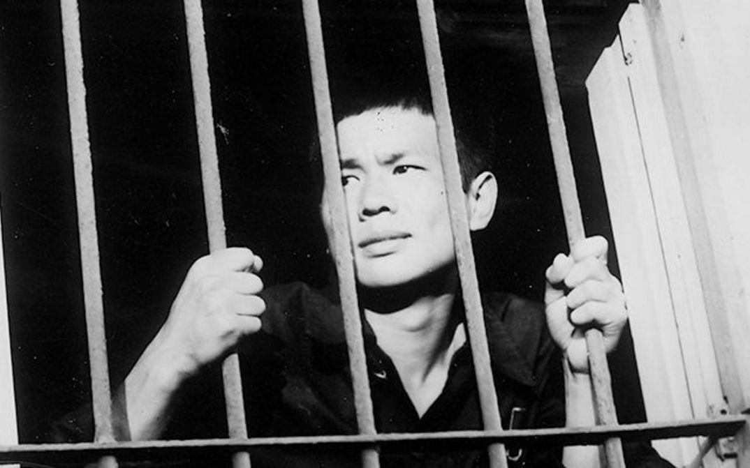 Film still from BAD BOYS: A young man clings to the bars of a barred window.