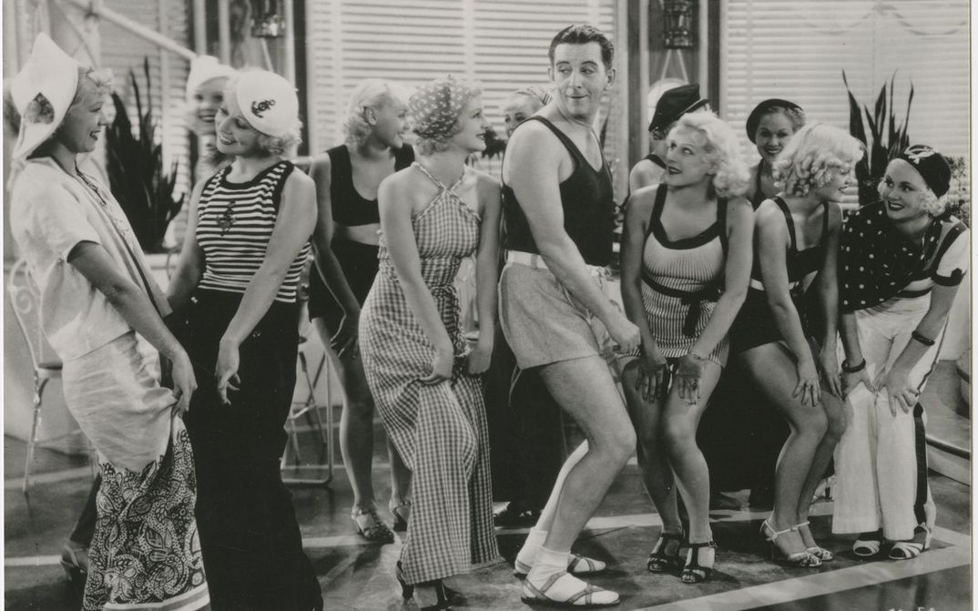 Film still from THE GAY DIVORCEE: Edward Everett Horton is dancing in shorts in the midst of a group of young women.