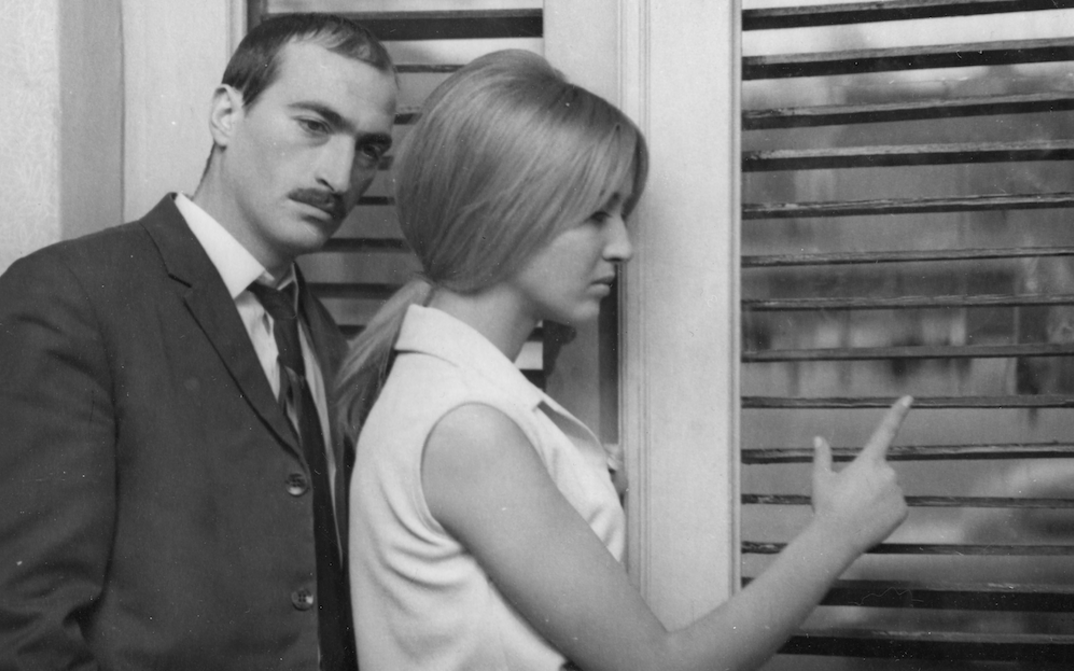 Film still from LIMITS: A man and a woman are standing at a window, both looking thoughtful.
