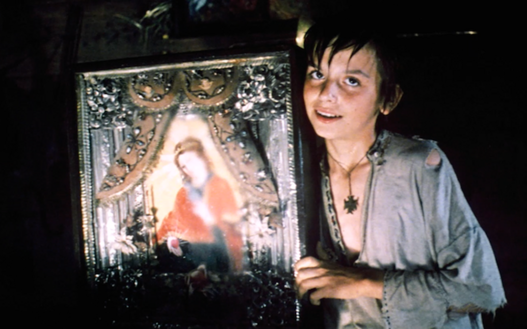 Film still from THE WHITE BIRD MARKED WITH BLACK: A boy holds up an icon.