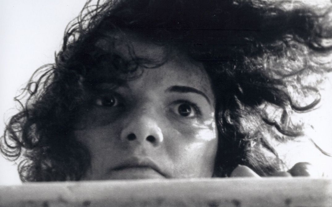 Film still from LIMITE: A young woman with disheveled hair gazes fixedly into the distance.