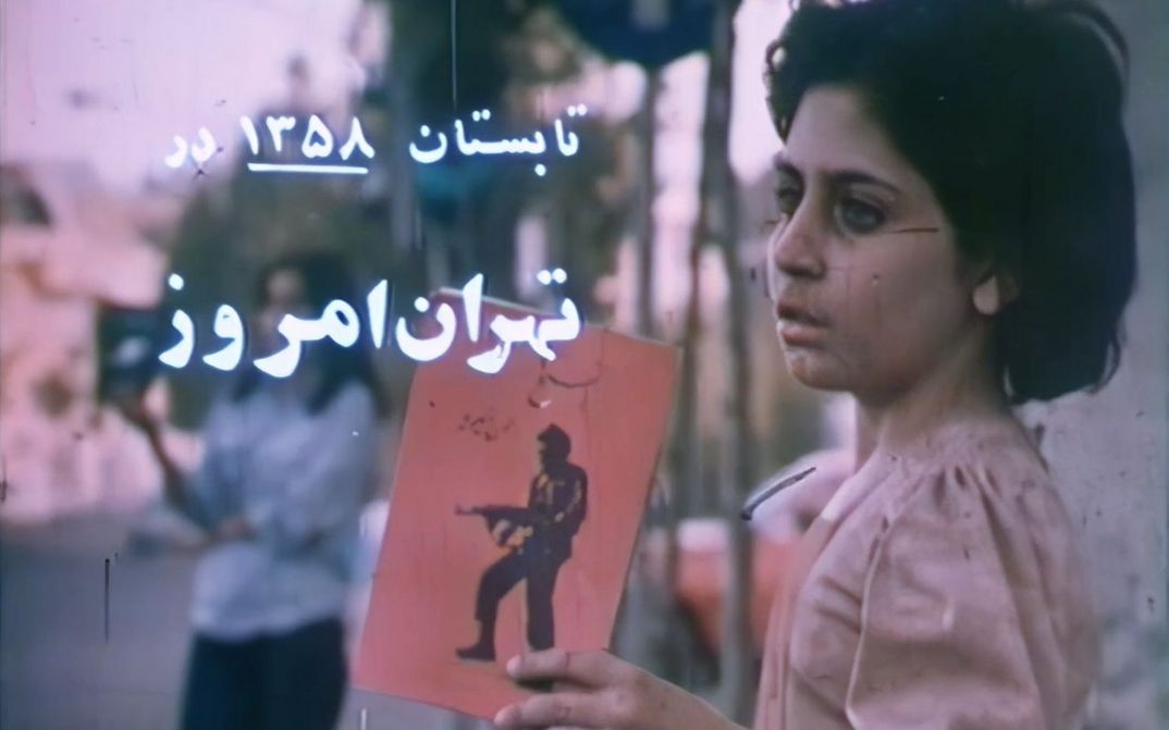 Film still from THE NEWBORNS: A girl holds up a picture of a man with a rifle.