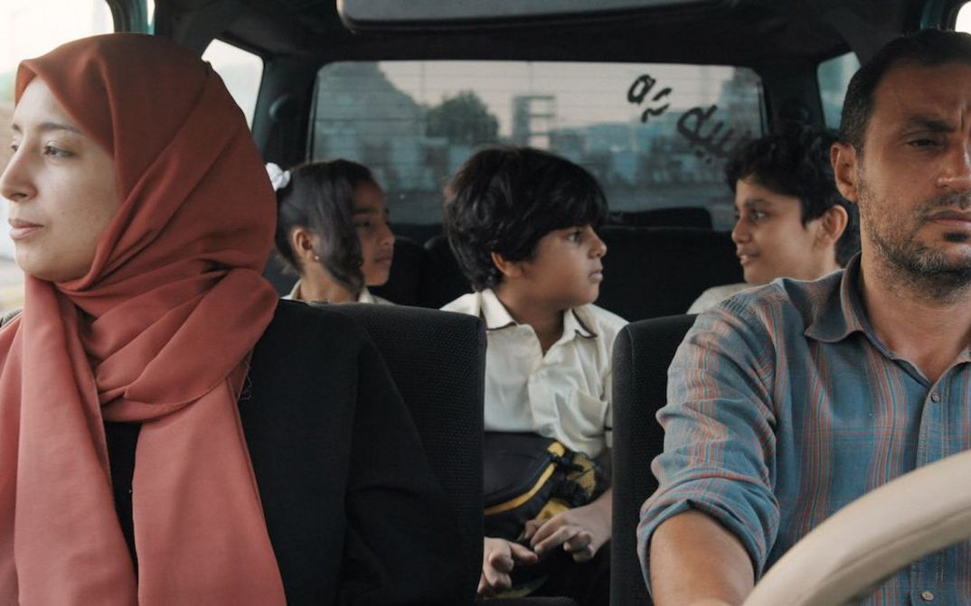Film still from THE BURDENED: A couple in a car with three children in the back seat.