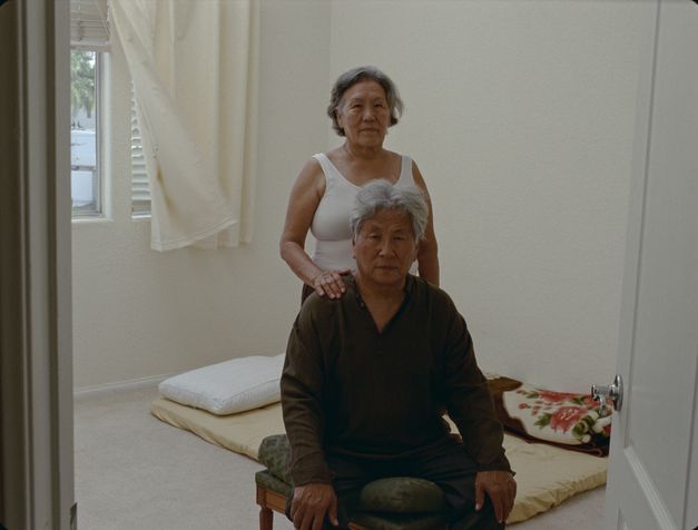 Filmstill aus dem Film „Pala Amala“ von Tenzin Phuntsog. Ein älteres Paar in der Mitte eines Raumes vor einer Matratze.