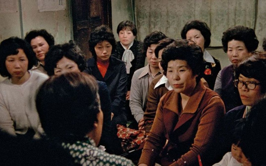 Film still from THE FAR ROAD: A group of women look at a person speaking.