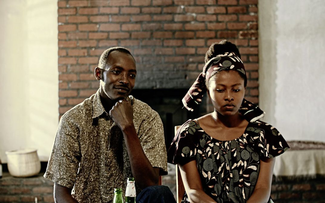 Filmstill from "The Bride" by. Myriam U. Birara. A woman looking down sadly is standing next to a man who is looking at her smiling.